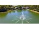 Scenic view of a community pond with a fountain surrounded by lush trees and condo buildings at 1400 Pine Glen Ln # B2, Tarpon Springs, FL 34688