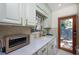 Galley kitchen with view to backyard featuring marble countertops, light green cabinets, and modern appliances at 1507 Legion Ln, Indian Rocks Beach, FL 33785