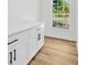 Bright laundry room featuring white cabinetry, quartz countertop and black hardware, with a window overlooking a lush landscape at 18238 Clear Lake Dr, Lutz, FL 33548