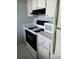 Bright kitchen with a white stove, black range hood, microwave, and white cabinets at 1975 W Bay Dr # 207, Largo, FL 33770