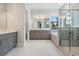 Bathroom featuring double sinks, walk-in shower, and soaking tub with a window at 207 Chippewa Ave, Tampa, FL 33606