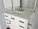 Close-up of a vanity with marble countertop, white cabinets, and bronze fixtures in a bathroom at 2810 Norwood Ln, Venice, FL 34292