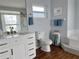 Bathroom featuring a vanity, toilet, tub, towel rack, and framed art pieces on light blue walls at 2810 Norwood Ln, Venice, FL 34292