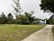 Expansive exterior view of the home's exterior with mature trees, landscaping, and gravel driveway at 2810 Norwood Ln, Venice, FL 34292