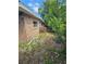 Brick home exterior with visible plumbing, small window and green foliage at 3714 E Ellicott St, Tampa, FL 33610