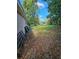 Backyard featuring a partial view of the house, mature trees, and a grassy area, with a car parked in the distance at 3714 E Ellicott St, Tampa, FL 33610