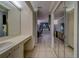 Hallway with mirrored doors, leading to a bathroom featuring white cabinetry and tile floors at 39650 Us Highway 19 N # 743, Tarpon Springs, FL 34689