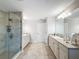 Bright bathroom with walk-in shower, double sink vanity, and travertine tile floor at 4024 Woods Rider Loop, Odessa, FL 33556
