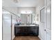 Bathroom featuring a dark vanity with granite countertops, a framed mirror, and a glass-enclosed shower at 4024 Woods Rider Loop, Odessa, FL 33556