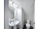 Charming half bathroom featuring pedestal sink, round mirror and wood look tile floor at 4024 Woods Rider Loop, Odessa, FL 33556