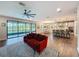 Open layout of living room and kitchen with backyard view and a stylish red sofa in a well-lit setting at 4024 Woods Rider Loop, Odessa, FL 33556