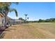 Spacious backyard with mature trees, golf course views, and a glimpse of the home with screened-in patio at 5113 Epping Ln, Zephyrhills, FL 33541