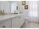 Bright bathroom featuring a white vanity with a solid surface top, decorative art, and a window with privacy sheers at 5113 Epping Ln, Zephyrhills, FL 33541