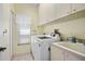 Functional laundry room with modern washer, dryer, utility sink, lots of cabinet space, and bright natural light at 5113 Epping Ln, Zephyrhills, FL 33541