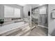 Bright bathroom featuring a soaking tub with wood paneling, a glass shower, and neutral gray walls at 5807 Cay Cove Ct, Tampa, FL 33615
