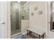 Bright bathroom featuring a glass shower with a tiled accent wall, a bench, and beach-themed wall art at 597 Ozona Village Dr, Palm Harbor, FL 34683