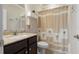 Cozy bathroom with dark vanity and sink, with a shower and toilet covered by a palm tree curtain at 597 Ozona Village Dr, Palm Harbor, FL 34683