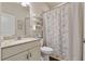 Bright bathroom with a marble vanity, decorative shelves, and shower with patterned curtain at 597 Ozona Village Dr, Palm Harbor, FL 34683