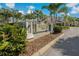 A lovely view of the community's entrance and signage amidst lush landscaping with palm trees at 597 Ozona Village Dr, Palm Harbor, FL 34683