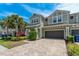Attractive exterior of the home featuring a paved driveway, two-car garage, and neatly manicured landscaping at 597 Ozona Village Dr, Palm Harbor, FL 34683