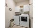 Bright laundry room with cabinets, stacked washer and dryer, and decorative wall art at 597 Ozona Village Dr, Palm Harbor, FL 34683