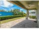 Outdoor patio with a fan, brick pavers, trimmed hedges, and an enclosed backyard at 597 Ozona Village Dr, Palm Harbor, FL 34683