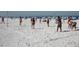 People playing volleyball on a sandy beach, with beachgoers and umbrellas in the background at 600 Bayway Blvd # 304, Clearwater, FL 33767