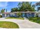 Attractive light blue home with solar panels, a well-kept lawn, and a curved driveway at 6207 Gulfport S Blvd, Gulfport, FL 33707