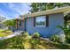 Close-up of a blue home with wooden shutters, tropical plants, and a stone walkway at 6207 Gulfport S Blvd, Gulfport, FL 33707