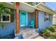 Inviting front porch with light blue door, wood pillars, stone steps and green chair at 6207 Gulfport S Blvd, Gulfport, FL 33707