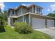 Two-story home featuring an attached two-car garage, neutral siding, a manicured lawn, and a colorful shrub at 6922 Duffy Ln, Tampa, FL 33616
