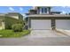 Image shows a two-car attached garage of the home, alongside partial view of a small landscaped lawn at 6922 Duffy Ln, Tampa, FL 33616