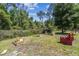 Wooded backyard with garden beds and red painted outdoor furniture set at 6938 Coronet Dr, New Port Richey, FL 34655