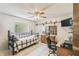 Bedroom with neutral walls, ceiling fan, checkered bedspread, and a work desk, creating a multi-use space at 6938 Coronet Dr, New Port Richey, FL 34655