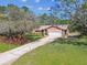 Single-story home with a well-manicured lawn, a long driveway, and a two-car garage at 6938 Coronet Dr, New Port Richey, FL 34655