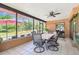 Enclosed patio featuring a dining table, fan, and a screened-in area overlooking the pool and backyard at 6938 Coronet Dr, New Port Richey, FL 34655
