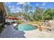 Private pool with stone waterfall feature, brick-paved patio, and lush backyard at 6938 Coronet Dr, New Port Richey, FL 34655
