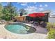 Backyard pool area featuring a waterfall feature, a red umbrella, and access to a screened in patio at 6938 Coronet Dr, New Port Richey, FL 34655