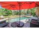 Backyard pool area with lounge chairs, an umbrella, and a waterfall feature surrounded by lush greenery at 6938 Coronet Dr, New Port Richey, FL 34655