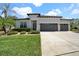 Beautifully landscaped home featuring a three-car garage, a well-manicured lawn, and a gray exterior at 7207 Peregrina Loop, Wesley Chapel, FL 33545