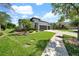 Home with a three-car garage and landscaped yard on a sunny day with blue skies and palm trees at 7207 Peregrina Loop, Wesley Chapel, FL 33545