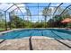 Relaxing screened-in pool with clear blue water and brick patio, set against a backdrop of lush greenery and blue skies at 7207 Peregrina Loop, Wesley Chapel, FL 33545