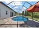 Relaxing screened-in pool featuring brick pavers, a blue sky view, and an orange umbrella at 7207 Peregrina Loop, Wesley Chapel, FL 33545