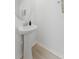 Cozy powder room featuring sleek pedestal sink, round mirror, and neutral-toned wood flooring at 7509 S Sherrill St, Tampa, FL 33616