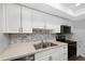 Modern kitchen features white cabinets, stainless steel appliances, and a stylish tile backsplash at 782 Village Lake N Ter # 102, St Petersburg, FL 33716