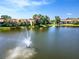 Scenic lake view with a fountain, mature trees, and a well-maintained condo in the background at 782 Village Lake N Ter # 102, St Petersburg, FL 33716