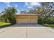A two-car garage with decorative windows sits beside a concrete driveway and is surrounded by lush landscaping at 9611 125Th N St, Seminole, FL 33772