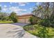 A two-car garage is visible from a concrete driveway, and surrounded by lush landscaping and a red tile roof at 9611 125Th N St, Seminole, FL 33772