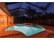 Screened pool area with a spa, covered patio and pavers, as seen at night at 9611 125Th N St, Seminole, FL 33772