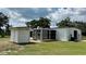 View of the barn with light colored metal exterior, black trim, and a screened outdoor seating area at 10101 Bryant Rd, Lithia, FL 33547